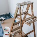 A messy stepladder and painting tools set up for a home interior renovation project.